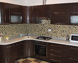 Угловая коричневая кухня с глянцевыми пленочными радиусными фасадами.